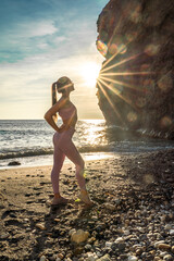 Wall Mural - Girl gymnast is training on the beach by the sea sunset. Does twine. Photo series.