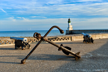 two old cannons, an anchor, the pebble beach, the lighthouse and the pier at Le Tréport, Seine-Maritime department in Normandy, France.