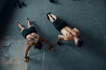 Sticker - Top view of young fit couple doing push-ups in gym together