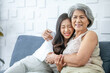 © todja - Asian grandma and granddaughter hugged with happy mood on the sofa in home.