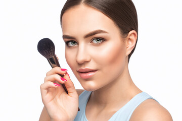 Wall Mural - Portrait of a beautiful brunette girl with beautiful fresh makeup and healthy clean skin.Makeup artist holds a powder brush in her hands. Professional makeup concept