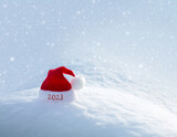 Fototapeta Kuchnia - New year 2023 background with red Santa hat on white snow.