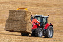 Agriculture - A Tractor Collecting Bales Of Hay