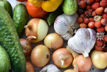 Wall Mural - Vegetables and berries close-up. Strawberries onions cucumbers and garlic in a pile of autumn harvest.