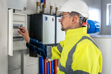 Wall Mural - Electrical technician looking focused while working in a switchboard with fuses.