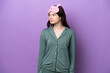 © luismolinero - Young Russian woman in pajamas isolated on purple background looking to the side