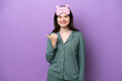 © luismolinero - Young Russian woman in pajamas isolated on purple background pointing to the side to present a product
