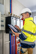 © puhimec - Electrical technician looking focused while working in a switchboard with fuses.