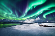 Northern Lights Over Lake. Aurora Borealis With Starry In The Night Sky. Fantastic Winter Epic Magical Landscape Of Snowy Mountains	