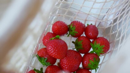 The camera lowers into a wicker string bag with ripe red strawberries brought from the garden. Eco-shop of useful products grown with care for human health and protection of the planet from plastic.