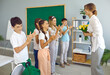 © Studio Romantic - Cheerful schoolchildren in school classroom congratulate their female teacher on International Teacher's Day. Preteen boys and girls give teacher bouquet of flowers and cheerfully applaud her.