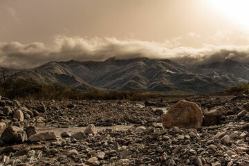 Sticker - Rocky desert with clouds covering the hills in the background  under sunlight