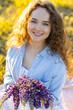 Beautiful young girl in a white dress, straw hat, with picnic and bouquet of purple wild flowers on a meadow. Summertime, golden hour, sunset. Work life balance