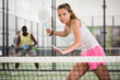 Young sporty woman padel player hitting ball with a racket on a hard court