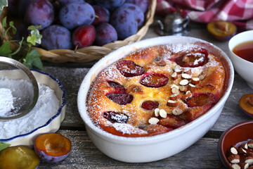 Wall Mural - Damson blue plum clafoutis (flan) and cup of tea, icing sugar and almonds dressing