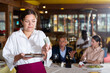 Portrait of upset waitress disappointed in small tip from guests at restaurant