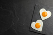 © New Africa - Heart shaped fried eggs on black table, top view. Space for text