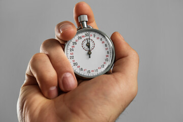 Man holding vintage timer on grey background, closeup