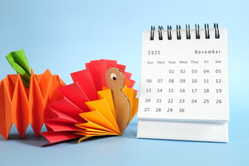 Wall Mural - Hello November 2022 with Thanksgiving Day concept. Desk calendar with turkey and pumpkin paper craft on blue background.