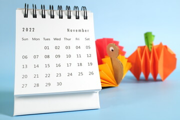 Wall Mural - Hello November 2022 with Thanksgiving Day concept. Desk calendar with turkey and pumpkin paper craft on blue background.