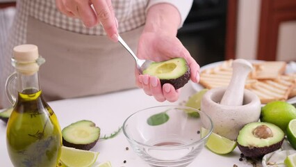 Canvas Print - Woman peeling a half of avocado fruit with a spoon