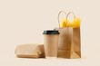 Takeaway paper coffee cup with lunch bag and burger box on beige. Snack delivery service. Coffee to go. Grab and go or carry out beverage. Disposable mockup packaging. Place for text. Minimal