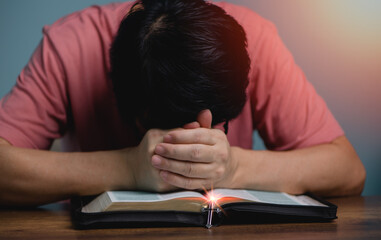 People holding hands head bow down  pray to God in the middle book holy bible book with cross necklace front of the holy bible.