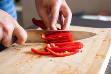 Canvas Print - man hands cutting red pepper close up on wooden board