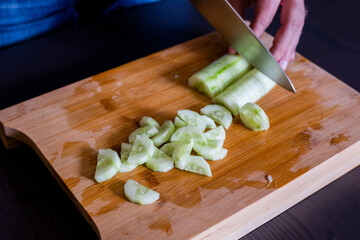 Canvas Print - man hands cutting fresh cucumber close up