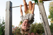 © Westend61 - Cheerful boy hanging upside down on horizontal bar