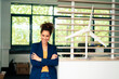 © Westend61 - Confident businesswoman with arms crossed by wind turbine model at office