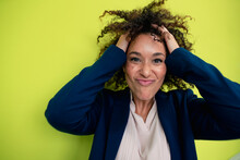 Playful businesswoman with hands in curly hair