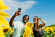 © Westend61 - Happy man with woman taking selfie through mobile phone in sunflower field