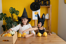 Smiling Girls Playing With Pumpkin On Table At Home