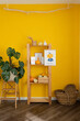 © Westend61 - Wooden rack with decor amidst potted plant and basket in front of yellow wall