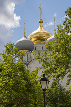 Golden And Gray Domes Of The Orthodox Church With Holy Crosses, Greenery And A Lantern. Novodevichy Convent In Moscow.  Cloudy Sky On A Summer Day.
