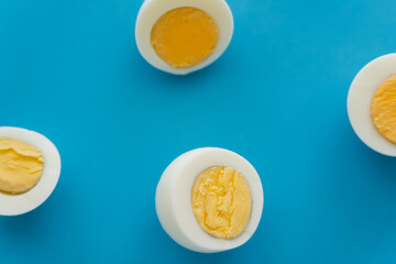 Wall Mural - Top view of cut boiled eggs on blue surface.