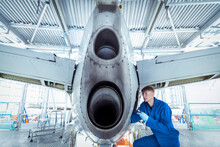 Apprentice Aircraft Maintenance Engineer Inspecting Tail Section Of Aircraft