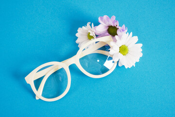 Wall Mural - trendy eyeglasses and flowers on blue background