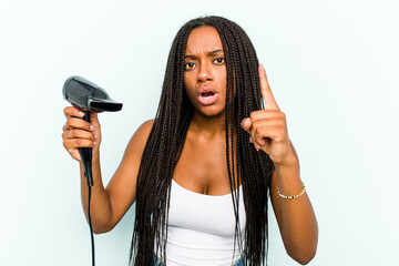 Young African American woman holding a hairdryer isolated on blue background having an idea, inspiration concept.