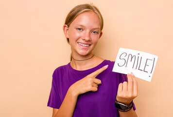 Little caucasian woman holding a smile placard isolated on beige background