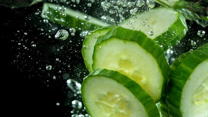 Aufkleber - Super slow motion of falling cucumber slices into water. Isolated on black background. Filmed on high speed cinema camera, 1000fps. Speed ramp effect.