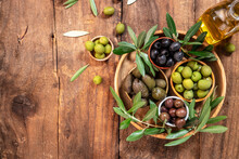 Mixed Types Of Olive In The Bowls And Olive Oil On A Wooden Background, Banner, Menu, Recipe Place For Text, Top View