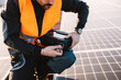 © dusanpetkovic1 - Cropped picture of worker opening toolbox while crouching on the rooftop covered with solar panels.