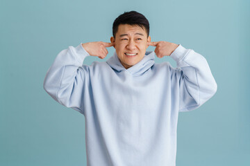 Wall Mural - Brunette adult asian man plugging his ears with hands