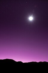 Sticker - Vertical shot of a purple sky with a shining star and silhouettes of hills