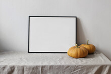 Moody Autumn Still Life. Landscape Black Picture Frame Mockup. Orange Pumpkins On Linen Table Cloth. White Wall Background. Minimal Rustic Interior, Neutral Color. Halloween, Thanksgiving Concept.