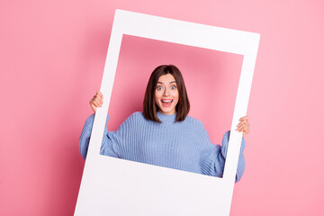 Poster - Portrait of young beautiful girl photoshoot smiling grimace party holding photo frame isolated on pink color background.