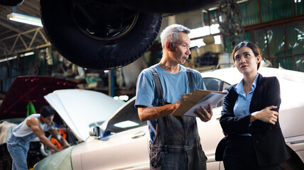 Wall Mural - Asian young woman customer talking with owner and mechanic worker at car repair service and auto store shop.