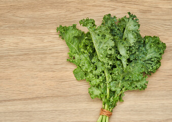 Wall Mural - top view fresh green Kale leaves bunch leaf cabbage on wooden table background. green kale or leaf cabbage                                                   